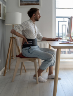 man sitting at computer while wearing a back brace